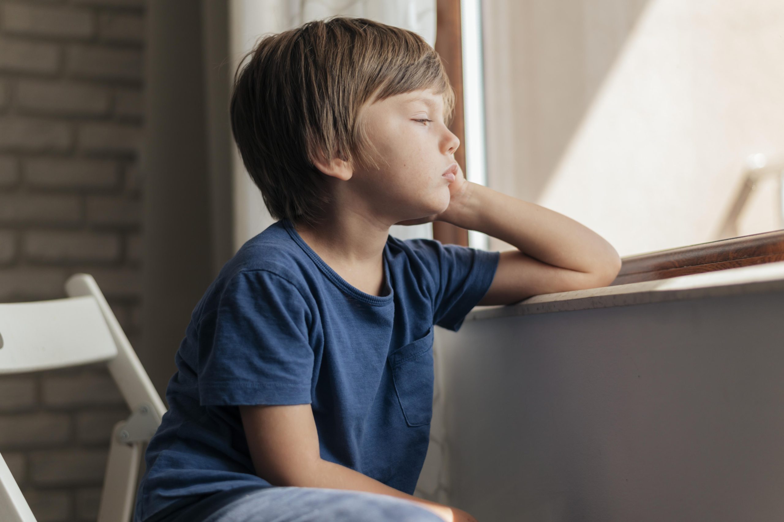 sad child looking through window quarantine scaled